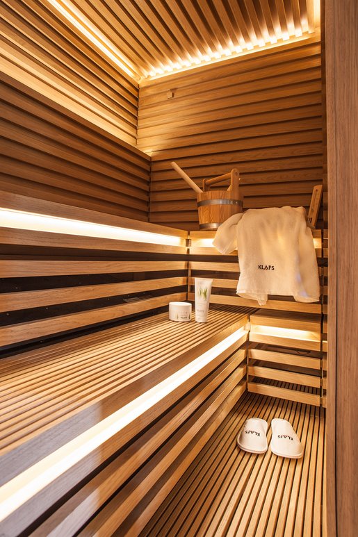 Het unieke gezicht van deze sauna van Matteo Thun wordt rondom gekenmerkt door het samenspel van eiken latten en voegen. De kachel wordt ruimtebesparend en kindveilig opgeborgen onder de bank.
